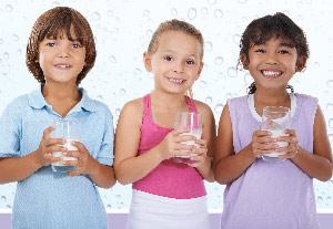 three school age kids with glasses of milk
