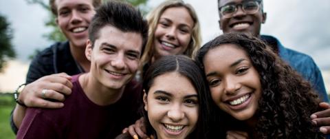 Grupo de adolescentes multiculturales sonriendo y mirando a la cámara