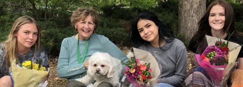 group photo of director Laurie Klith with three young women holding flowers