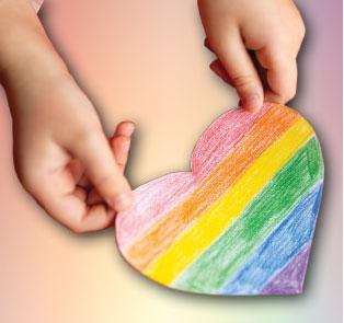 child's hands holding rainbow heart